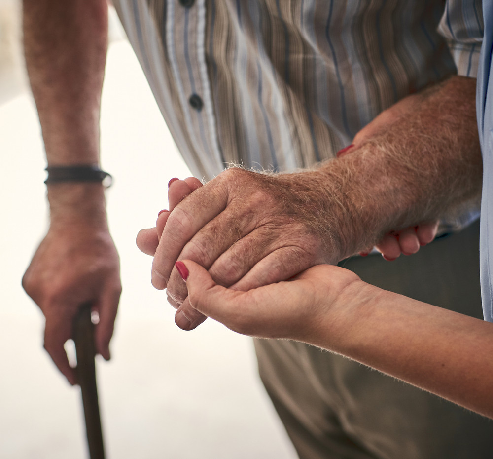 Une infirmière soutient la main d’un patient à domicile